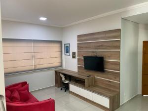 a room with a desk with a television and a red chair at Sobrado Premium - Zona Sul in Maringá