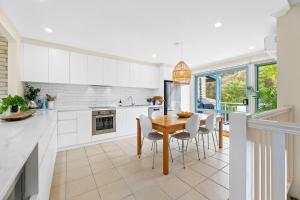 a kitchen with white cabinets and a wooden table and chairs at 2-Bed Townhouse with Outdoor Area in Long Beach