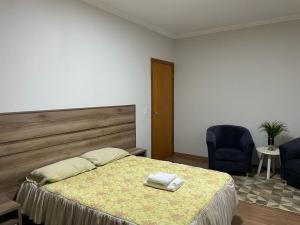 a bedroom with a bed and two blue chairs at Sobrado Premium - Zona Sul in Maringá