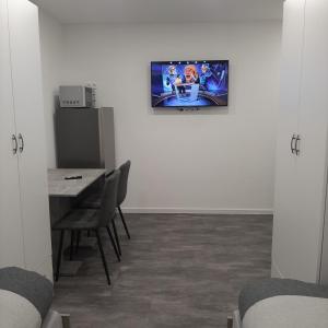 a room with a table and a television on a wall at Five Rooms in Sinsheim