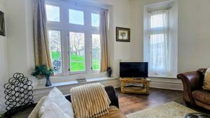 a living room with a couch and a television at Spring View Apartment in Buxton