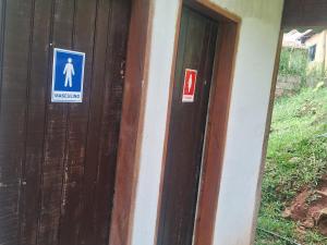 a wooden door with signs on the side of a house at Camping caminho das pedras in São Bento do Sapucaí