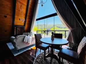 a table and chairs in a room with a large window at Romantic nature retreat | Hot tub and fireplace in São Pedro de Alcântara