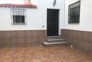 a black door on a white building with a brick floor at Enjoy Sevilla in La Rinconada