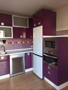 a kitchen with purple cabinets and stainless steel appliances at Enjoy Sevilla in La Rinconada