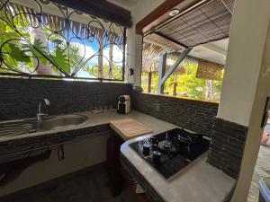 a kitchen with a stove and a sink and a window at Hamakana gîte vue mer in Grand-Bourg