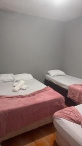a room with three beds with red and white sheets at Pousada Bem estar in Divinópolis