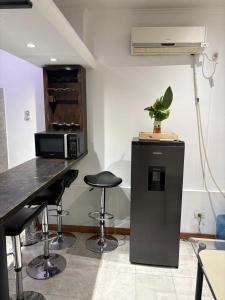 a kitchen with a counter with stools and a microwave at Dpto Céntrico con Asador in Chilecito
