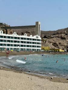 a hotel on the beach with people in the water at Cozy Garden by the Beach in Playa del Cura