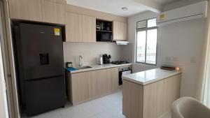 a kitchen with wooden cabinets and a black refrigerator at Cartagena Serena Del Mar INAWA in Cartagena de Indias +12 photos