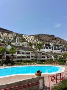 a large swimming pool with palm trees and buildings at Cozy Garden by the Beach in Playa del Cura