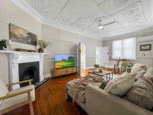 a living room with a couch and a tv at Aveline Cottage in Cessnock