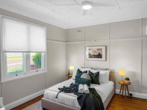a bedroom with a bed with green pillows and a window at Aveline Cottage in Cessnock