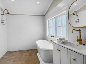 a bathroom with a sink and a toilet and a window at Aveline Cottage in Cessnock