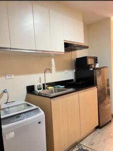 a kitchen with white cabinets and a sink and a stove at 3ff Megaworld, One Regis in Bacolod
