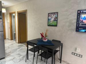 a dining room table with chairs and a television on the wall at Appartement de lux avec piscine in Mohammedia +10 photos
