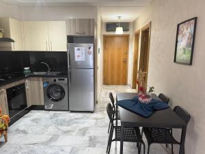 a kitchen with a table with chairs and a refrigerator at Appartement de lux avec piscine in Mohammedia