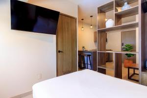 a bedroom with a bed with a flat screen tv on the wall at Rau Departamentos in Guadalajara