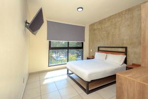 a bedroom with a white bed and a window at Rau Departamentos in Guadalajara
