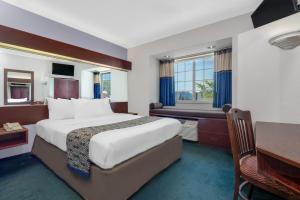 ロンドンにあるMicrotel Inn & Suites by Wyndham Londonのベッドとデスクが備わるホテルルームです。