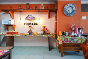 a restaurant with a table with food and a clock on the wall at Do Parque Pousada in Penha