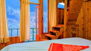 a bedroom with a bed and a large window at The Tree Hub Jibhi in Jibhi
