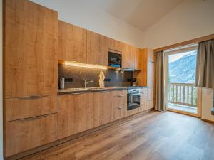 a kitchen with wooden cabinets and a large window at Glückauf in Krimml