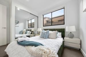 a bedroom with a large bed and two windows at Gregory Hills Haven Luxe in Gledswood Hills