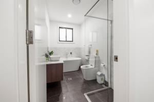 a bathroom with a tub and a sink and a shower at Gregory Hills Haven Luxe in Gledswood Hills +16 photos