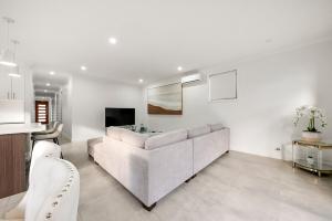 a white living room with a couch and a tv at Gregory Hills Haven Luxe in Gledswood Hills