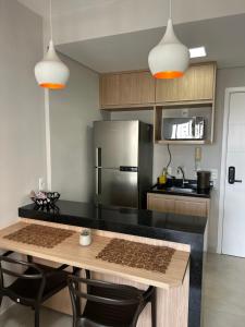 a kitchen with a table and a stainless steel refrigerator at Flat Duo JK. Lindo e completo in Sao Jose do Rio Preto
