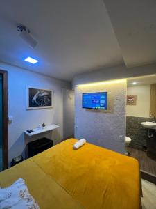 a bedroom with a yellow bed and a sink at Angel Hospedagem de quartos Self Check in in Vila Velha