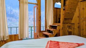 a bedroom with a bed and a large window at The Tree Hub Jibhi in Jibhi