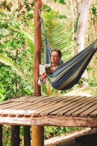 a man sitting in a hammock reading a book at Alya Jungle Casitas in San Juanillo