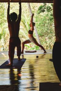 a couple of people doing yoga on a deck at Alya Jungle Casitas in San Juanillo