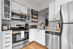 a kitchen with white cabinets and stainless steel appliances at Sub-Penthouse view condo in Downtown in Vancouver