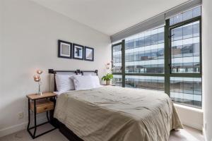 a bedroom with a bed and a large window at Sub-Penthouse view condo in Downtown in Vancouver