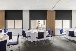 a conference room with white tables and blue chairs at Mantra MacArthur Hotel in Canberra