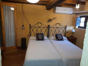 a bedroom with two beds with white sheets and black pillows at El Balcón de Mogarraz in Mogarraz
