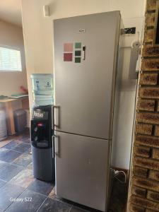 a stainless steel refrigerator in a kitchen with a trash can at De Kleine Kaap Guesthouse in Lady Grey