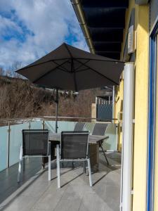 a table and chairs with an umbrella on a balcony at Komfortresidenz Natur in Weiz
