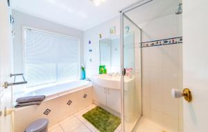 a bathroom with a tub and a sink and a shower at Brightside , Great family home near Airport in Craigieburn +30 photos