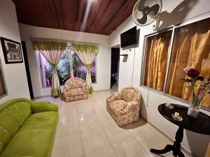 a living room with a green couch and two chairs at Casa Hotel Diana Luz in Villavieja