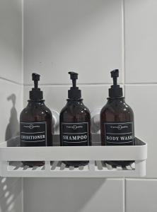 three bottles of soap on a shelf in a bathroom at Modern fully equipped studio with parking in Concepción +4 photos