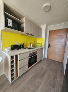a kitchen with yellow tiles and a counter top at Modern fully equipped studio with parking in Concepción