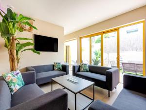 a living room with couches and a tv at Peaceful Getaway with Spa in Avelgem