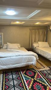 two beds in a room with a rug on the floor at Cinderella dahabya in Luxor
