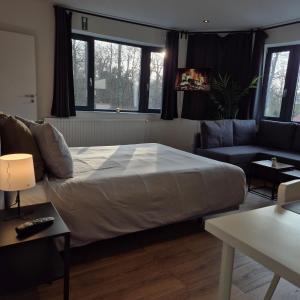 a bedroom with a large bed and a couch at Orient Herent - Boetiekhotel in Herent