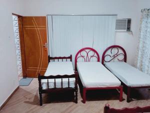 two beds in a room with two chairs at pousada benção in Aparecida
