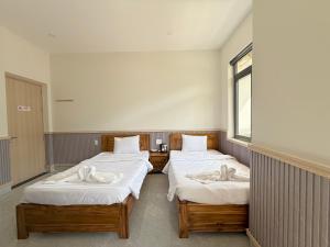 two twin beds in a room with a window at Motel Nam Nguyên in Buôn Kô Sir